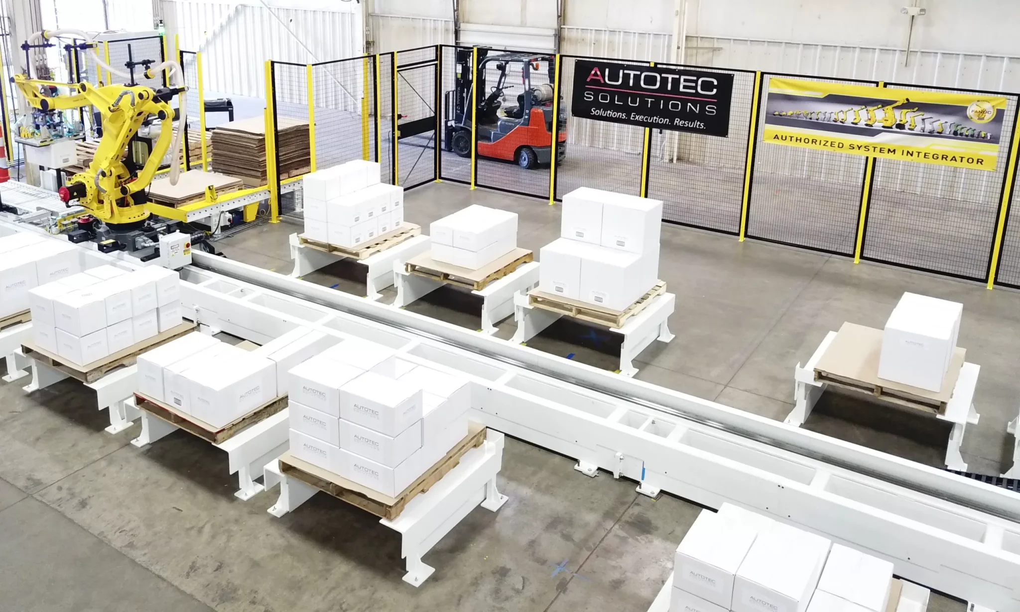 Autotec Solutions robotic palletizing system with warehouse mobile robots, Fanuc palletizer, and robotic transfer unit.